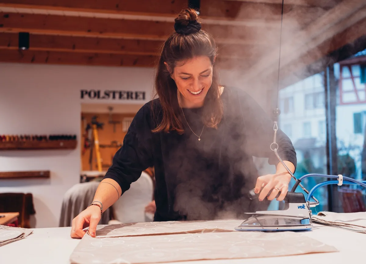 Ursina Steiner (Bild) und Alessandra Gobeli komplettieren das Team hinter Garekla Design. Eine Frau bügelt mit einem Bügeleisen ein Stück Stoff